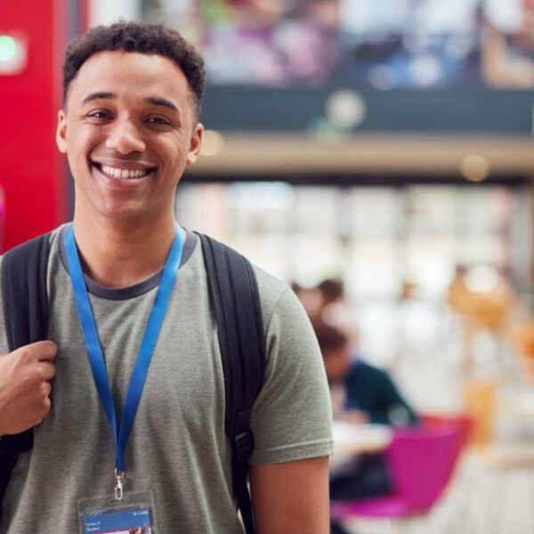 portrait of smiling male college student in busy communal campus building